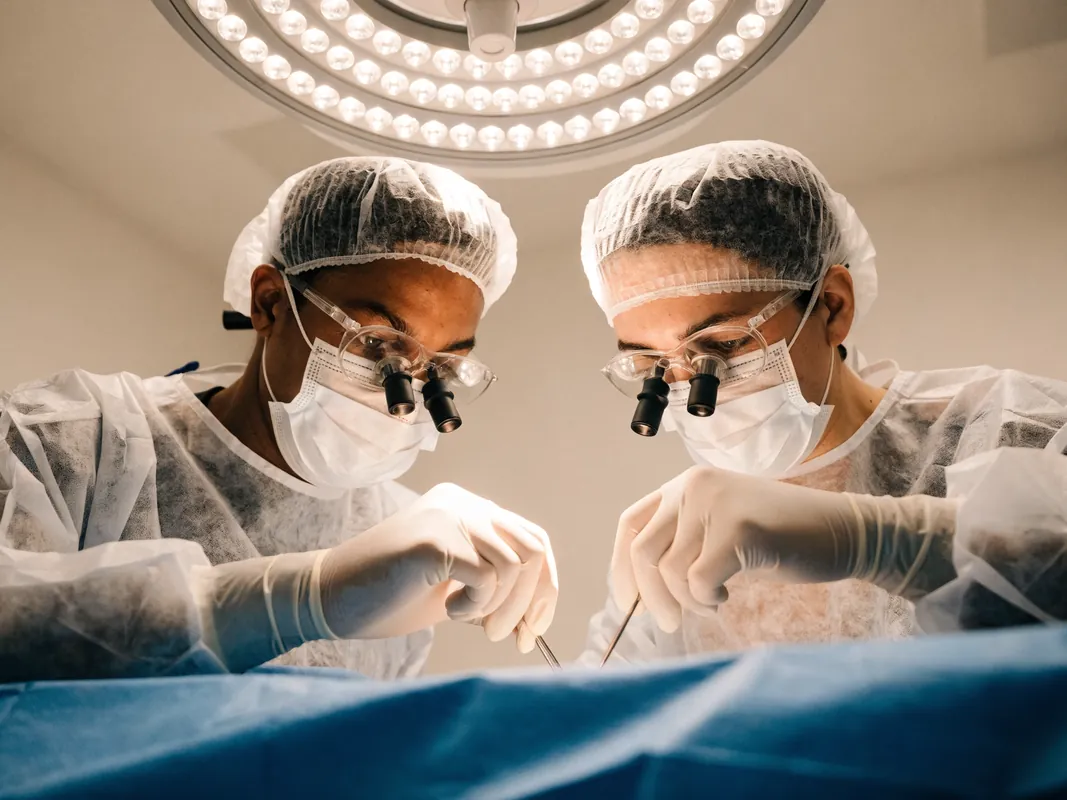 Surgeon and assistant working together over a sterile draped field during implant surgery