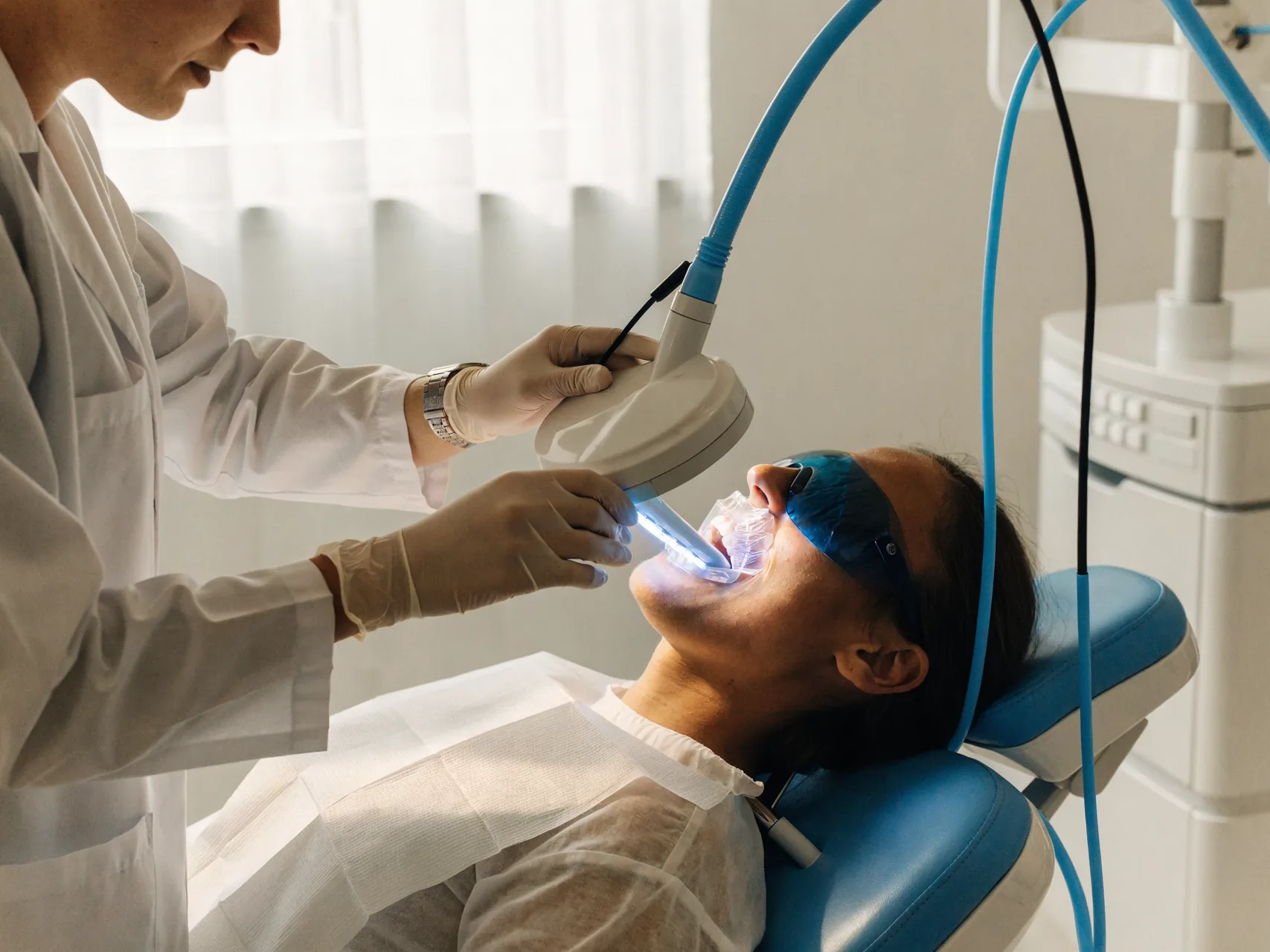 Patient undergoing an in-clinic LED whitening session with cheek retractor and protective eyewear in place