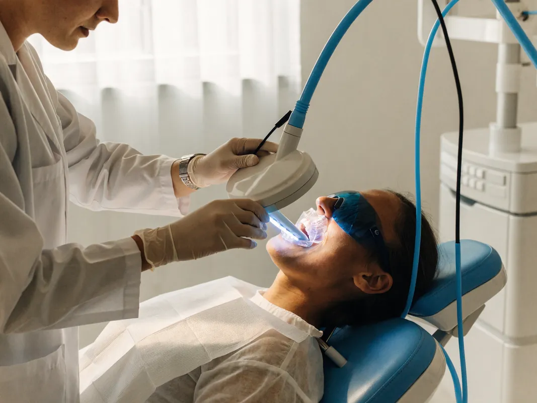 Patient undergoing an in-clinic LED whitening session with cheek retractor and protective eyewear in place